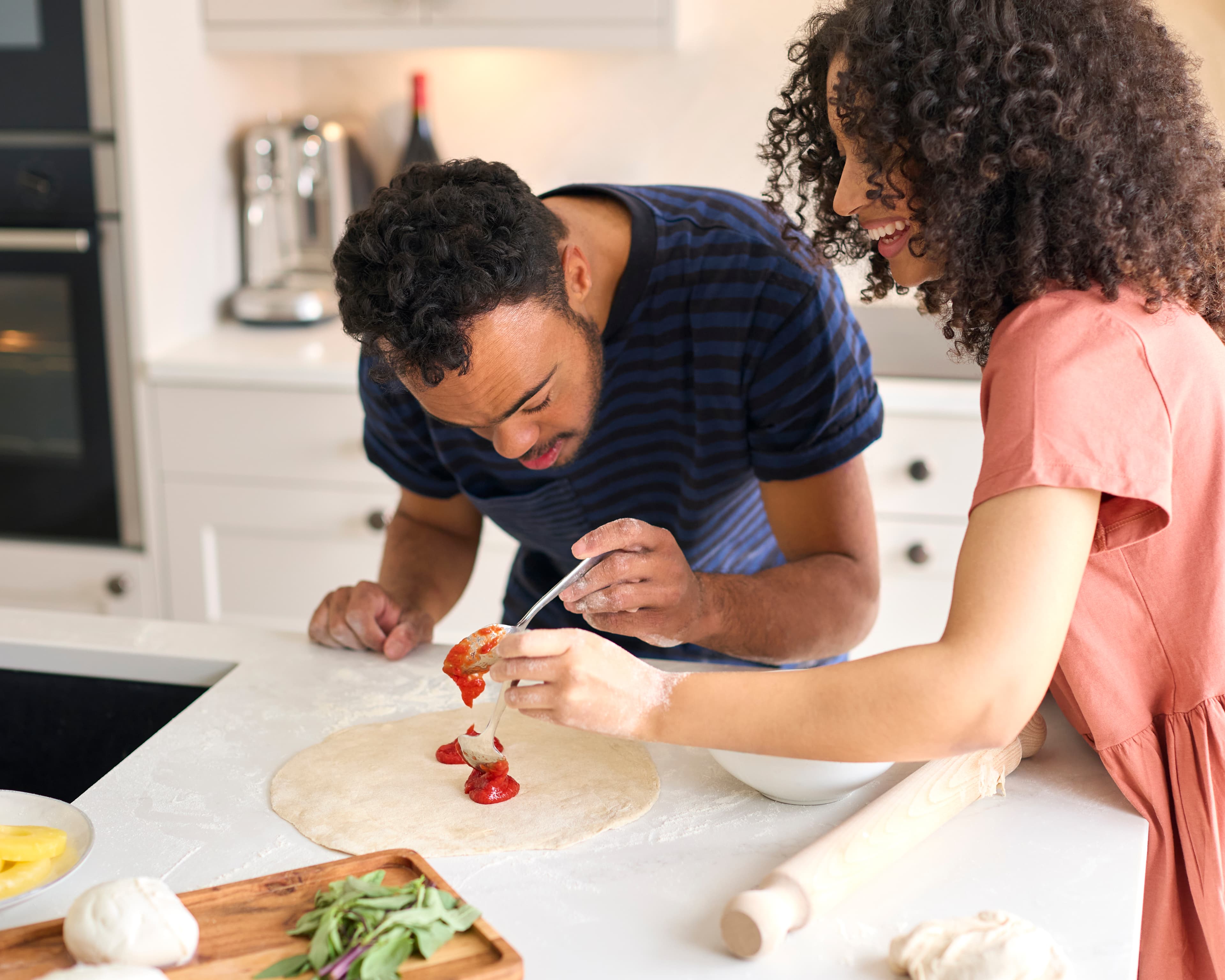 Couple making pizza together in kitchen